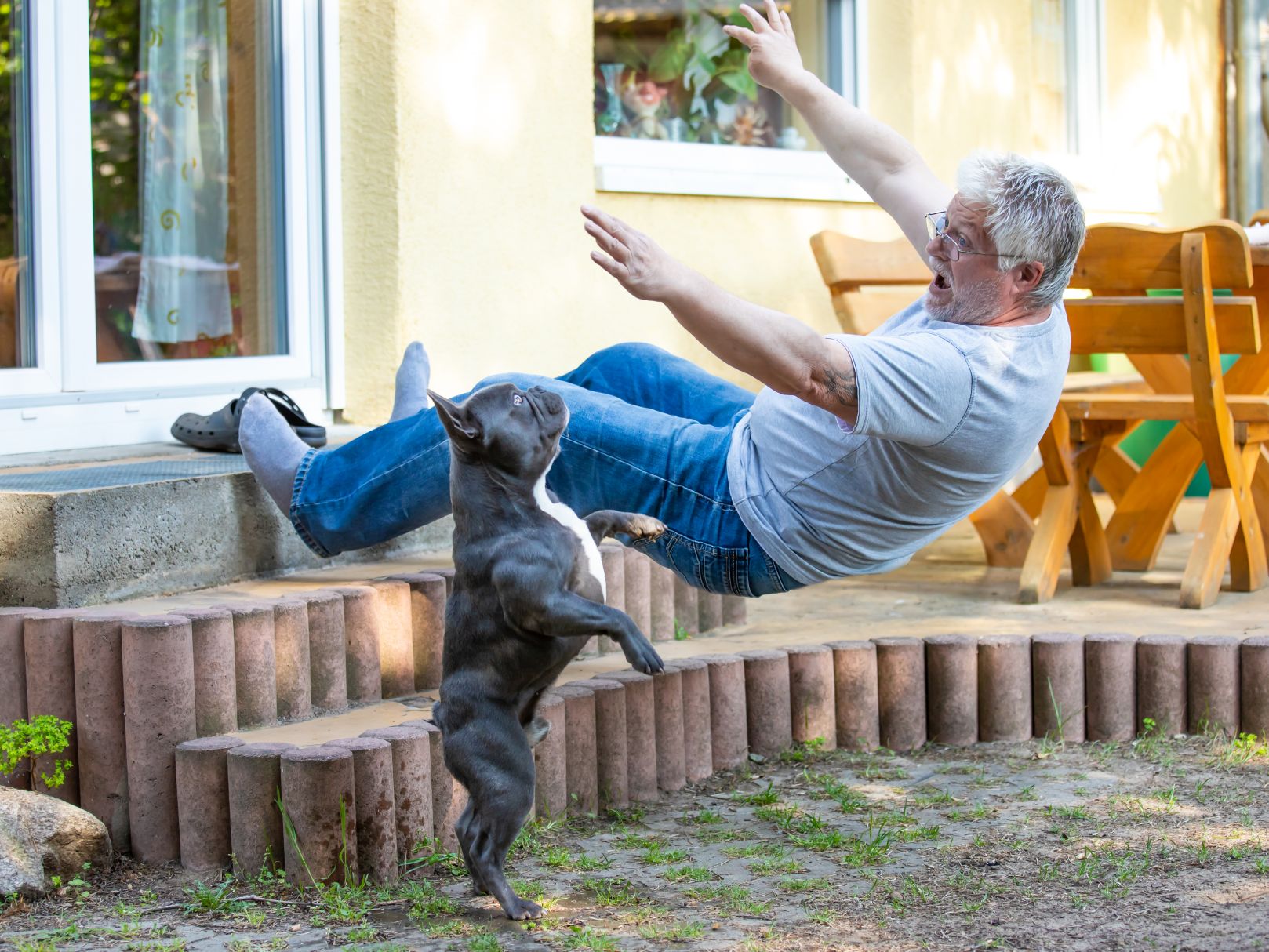 An older man has stumbled and falls down a flight of stairs. He