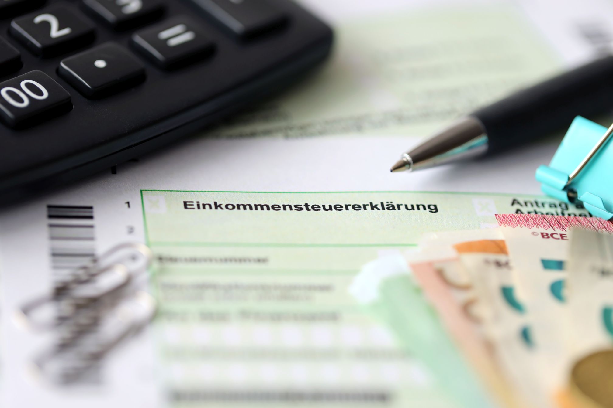 German income tax return form with pen and european euro money bills lies on accountant table close up. Taxpayers in Germany using euro currency as main to pay taxes