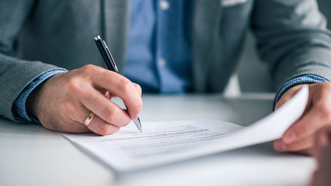 Businessman hand signing contract, close-up.